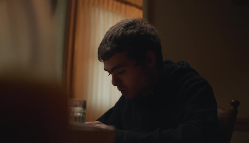 A young man is sitting down and eating some food