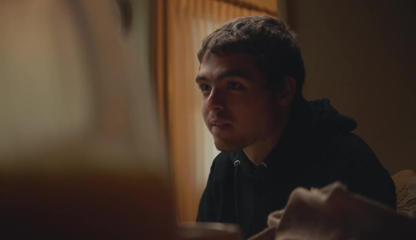 Man sitting at table listens to person talking and shakes his head