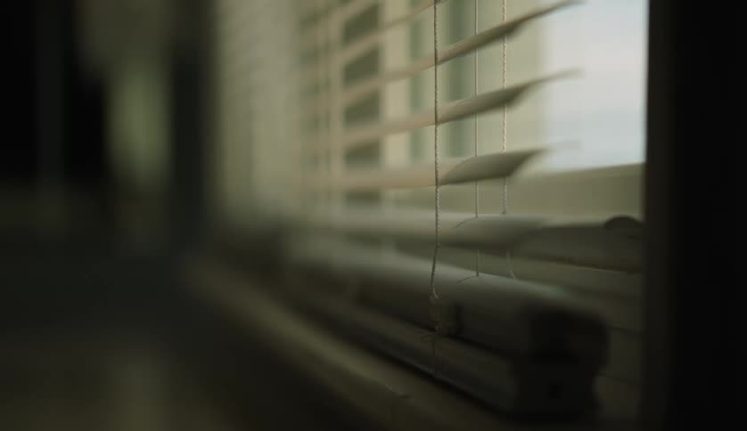 Blinds hang over a window as light shines in