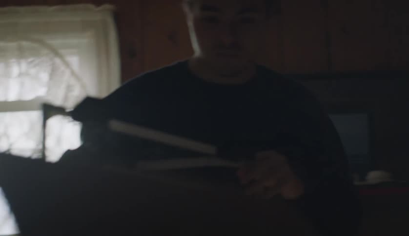 There is a young man carrying a basketball hoop inside of his home