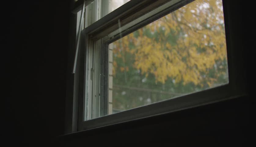 A person is shutting a window in their house