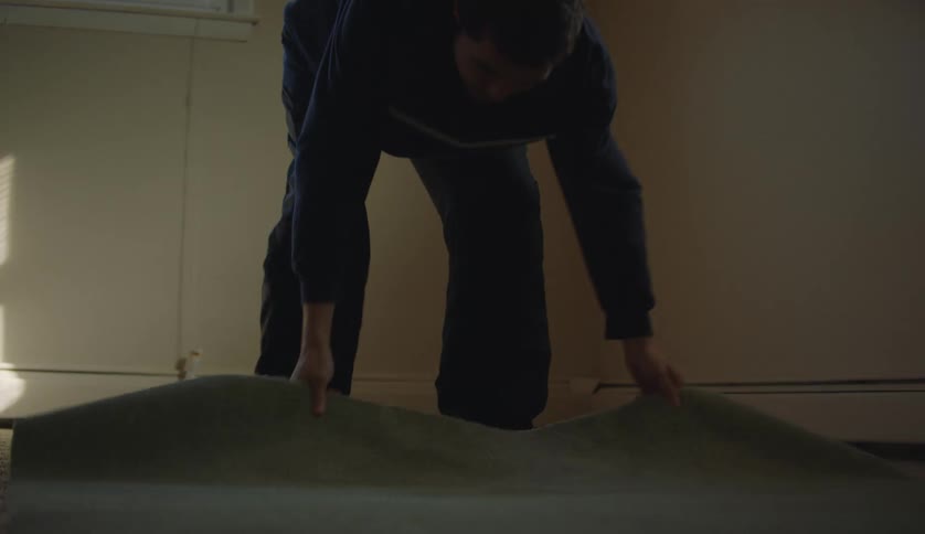 Male laying down a rug in a room