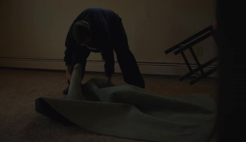 A man ripping up carpet in a home bedroom