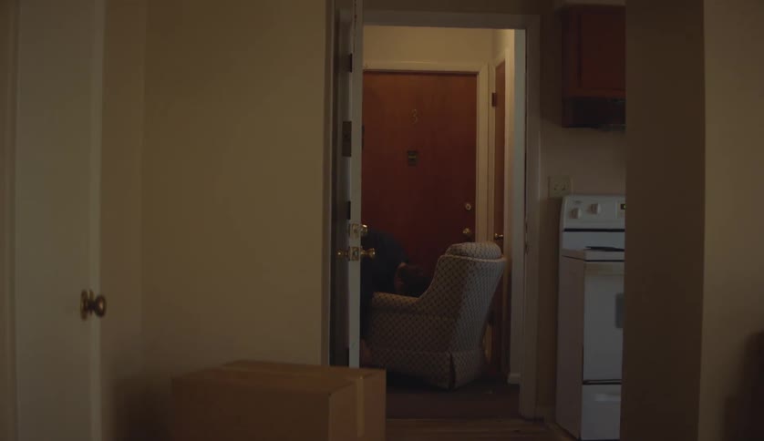 Male determined to move a sofa chair into a room from the hallway