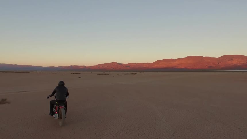 A man races along the desert on a motorcycle