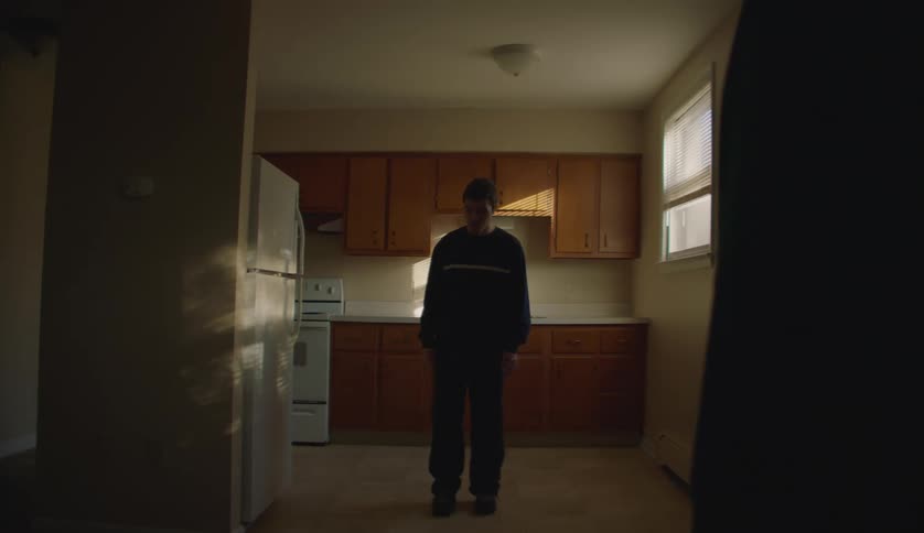 Grandmother standing on the living room instructs her grandson to come out of the kitchen