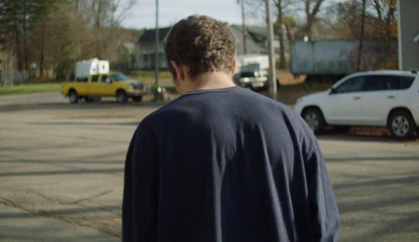 A male is walking on a road in a neighborhood