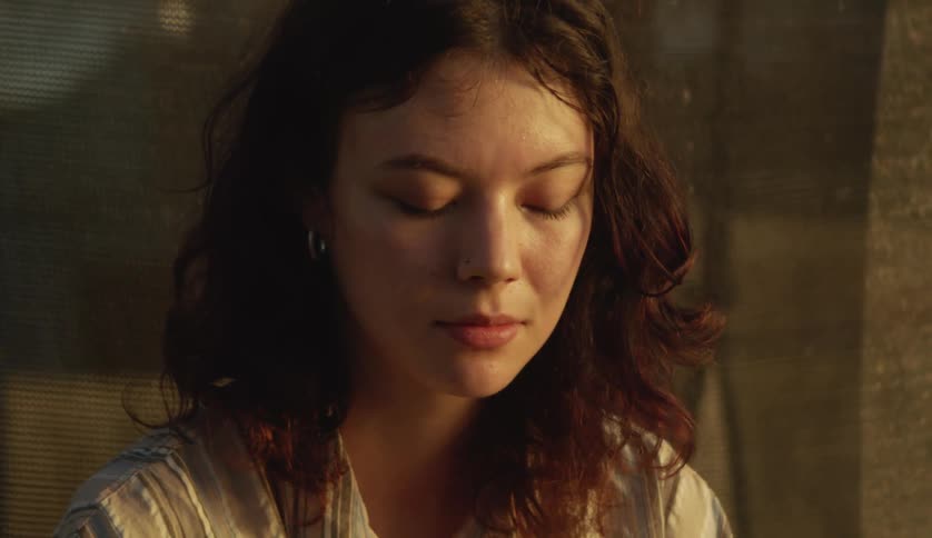 A woman is smiling and sitting by a window