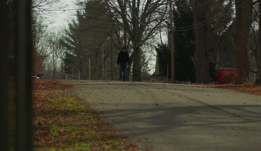 A young white man is walking down the street outside