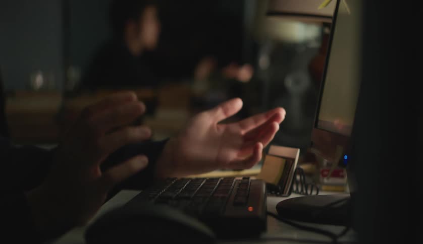 A man is holding his hands above the keyboard using one finger to press a key and then points at the screen