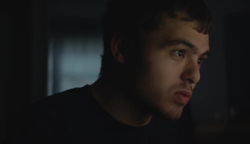 A male is standing indoors and looking at a window