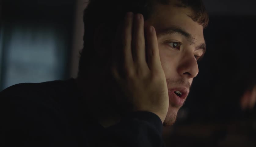 A male is sitting inside his house at night