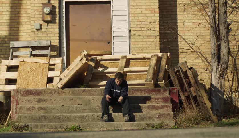A young teenage boy is sitting down on some stairs outside