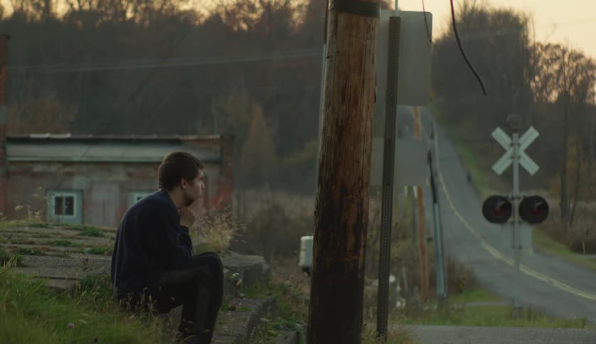 Man sitting at the side of a rural road at evening
