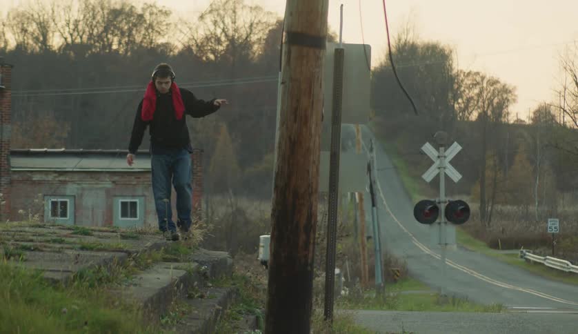 Young man walks carefully over the overgrown path near a country road