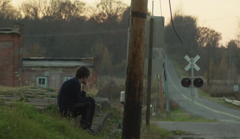 A boy sits by the road