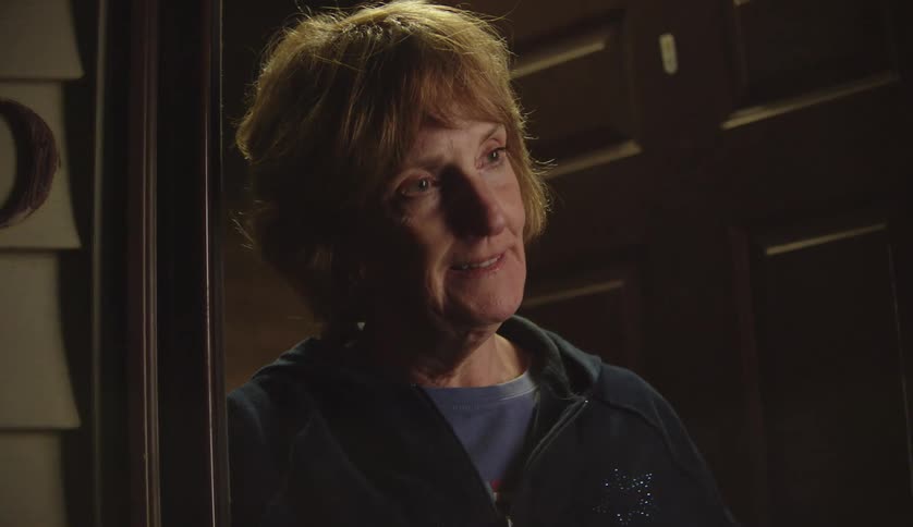 A woman brings a toothbrush to the door and hands it to someone and talks to them