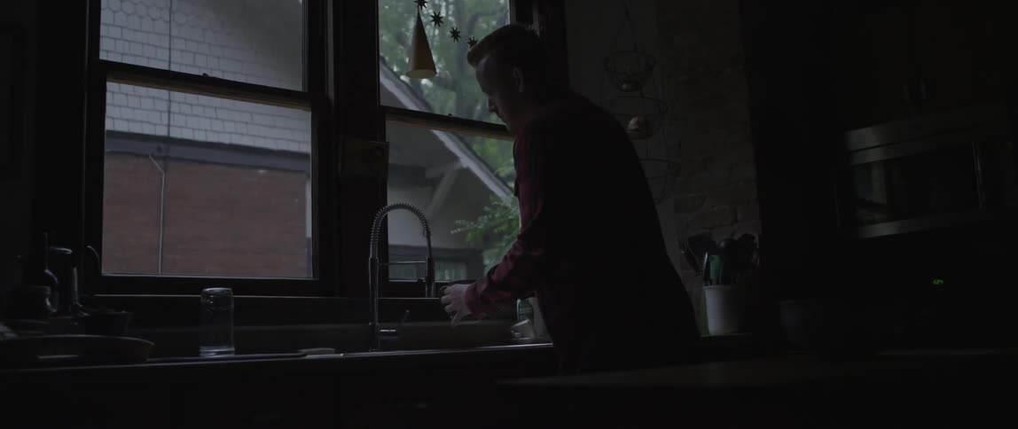 Man filling a cup with water from kitchen faucet