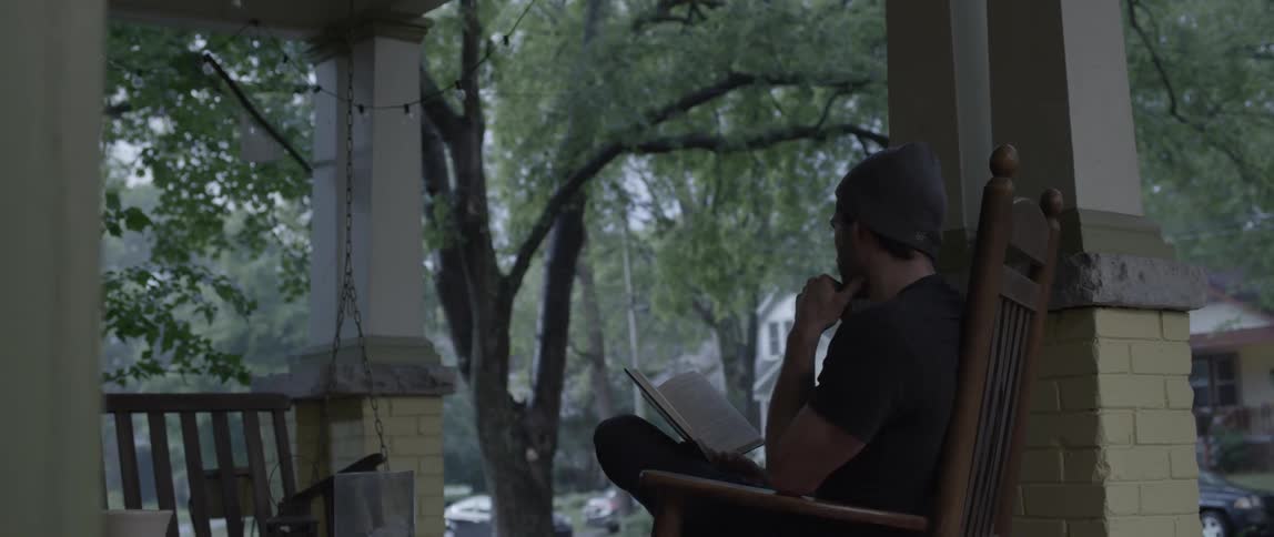 A man is sitting on a porch reading