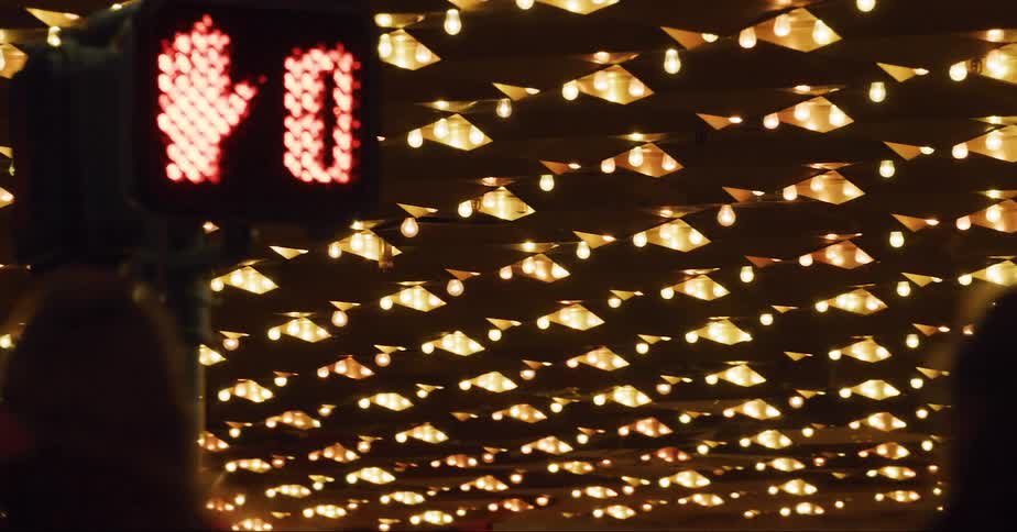 Two women cross the street at an intersection in front of a building with flashing lights
