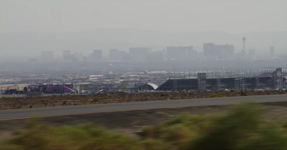 The city of las vegas can be seen in the distance from a distant roadway