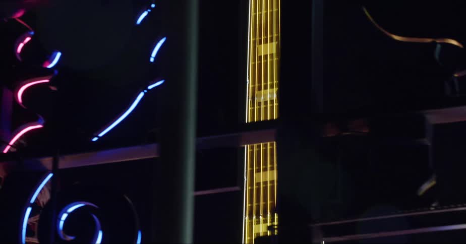 Looking through a window as a guitar model is lit up in the darkness of night
