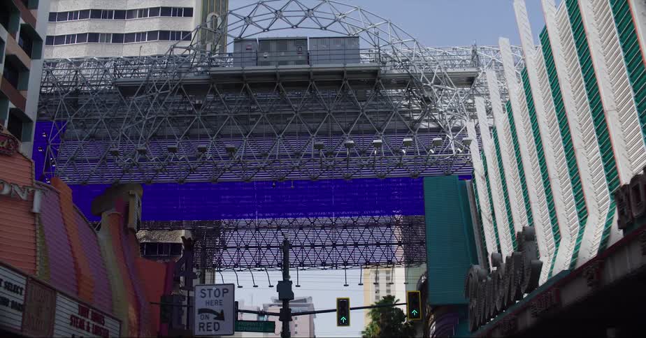 A car traveling beneath a bridge with colorful projections in a city