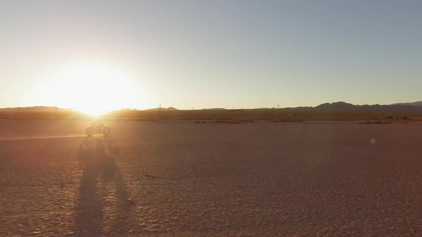 A person rides their motorcycle through the desert