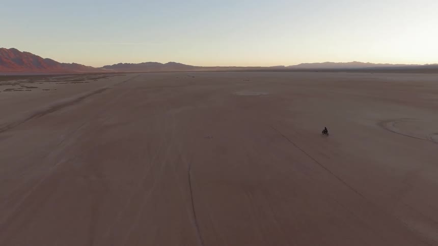 Someone riding a motorcycle through a desert