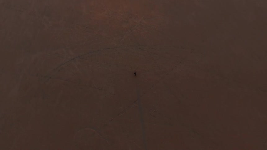 A motorcycle races along the desert below