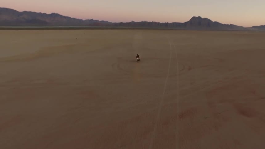 A person rides a motorcycle in the desert at midnight