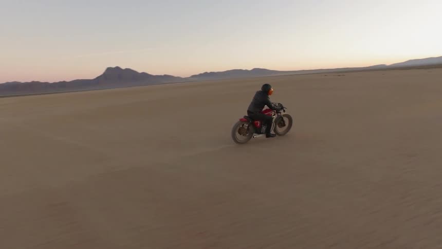 A motorcycle races along a desert