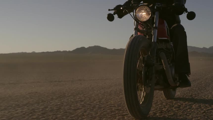 A person drives a motorcycle in the desert