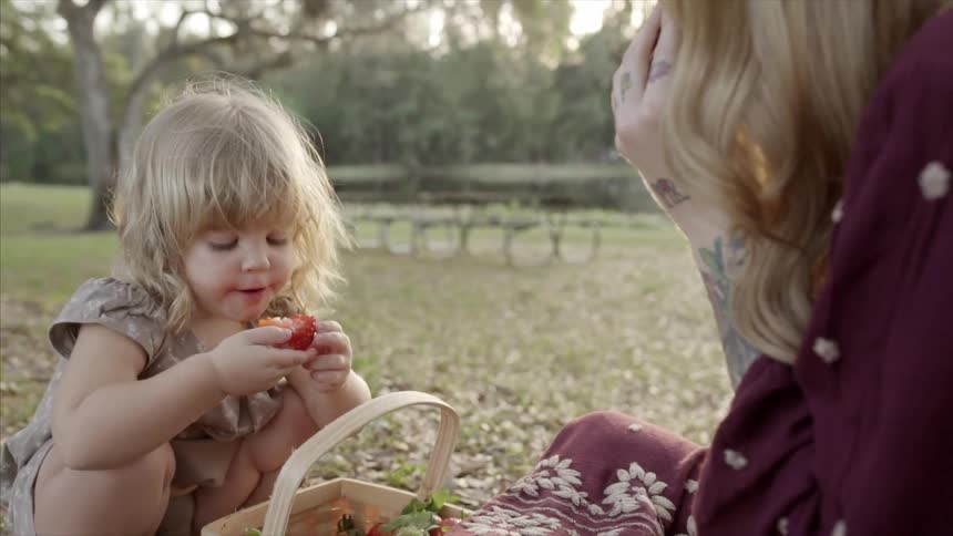 A girl and woman are having a picnic eating fruit