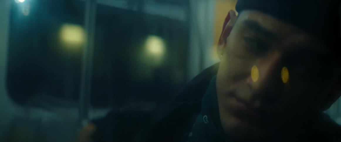 Close up of the face of a man riding a bus in the city at night