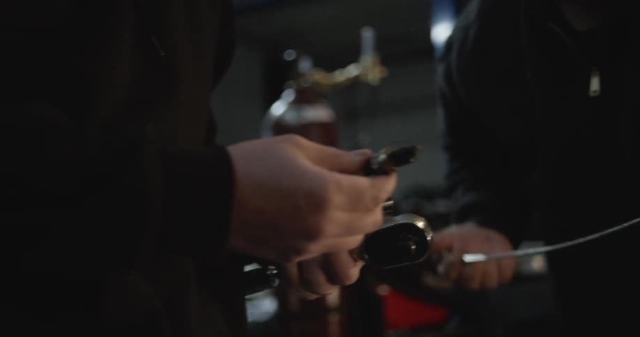Two mechanics handling the tools to fix the engine of a car inside a garage