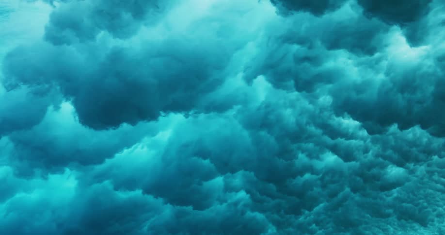 Underwater view of waves rolling overhead and sunlight reflecting as water splashes