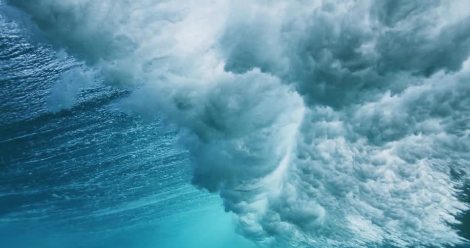 Rolling wave crashes over murky water creating bubbles