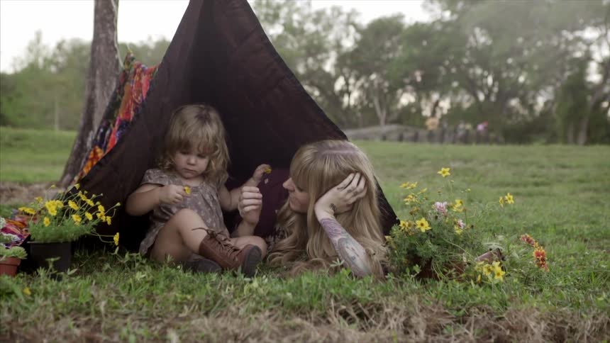 A woman and her child playing in a blanket tent