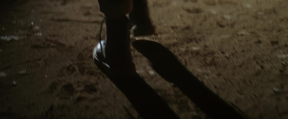 Woman wearing a pair of black boots and brown pants walks in the desert