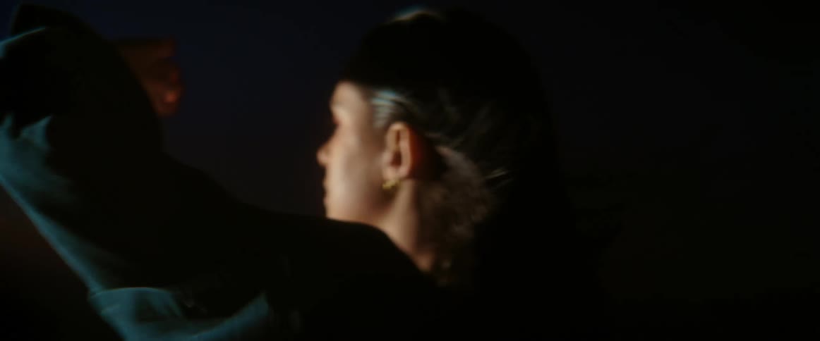 A woman is walking in the dark shielding her face from the strong wind