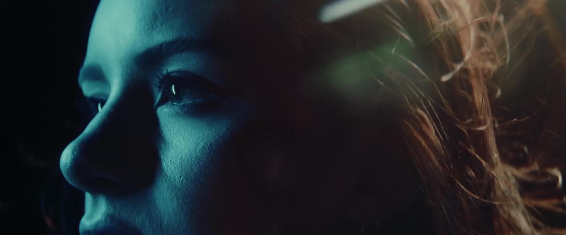 Blinking colored light shines on womans face as wind ruffles her hair