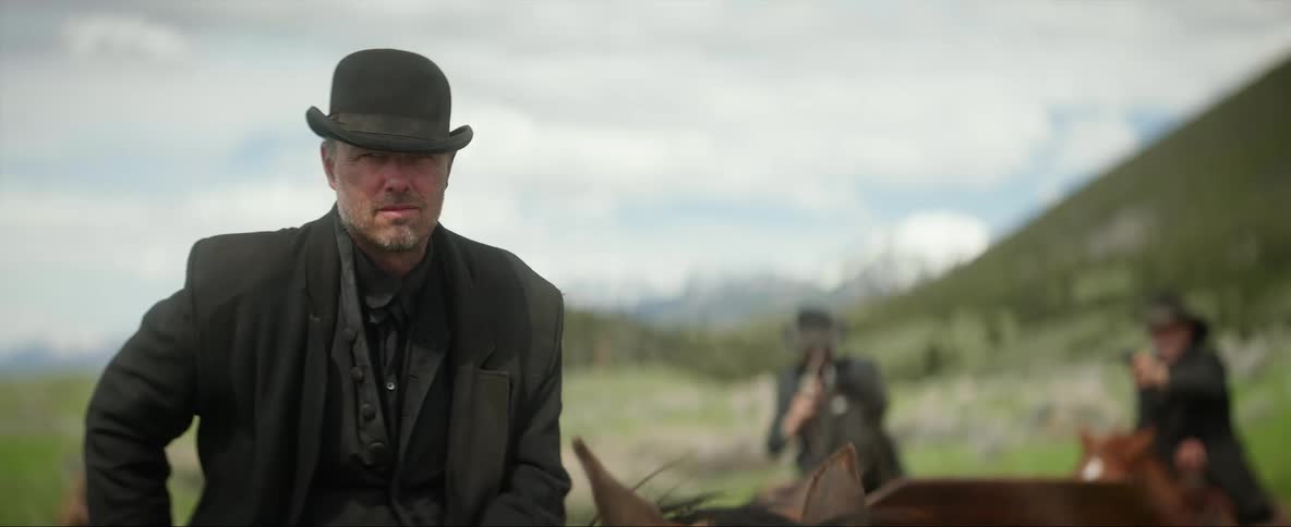 Cowboy sitting on a horse close to other men looking at the camera