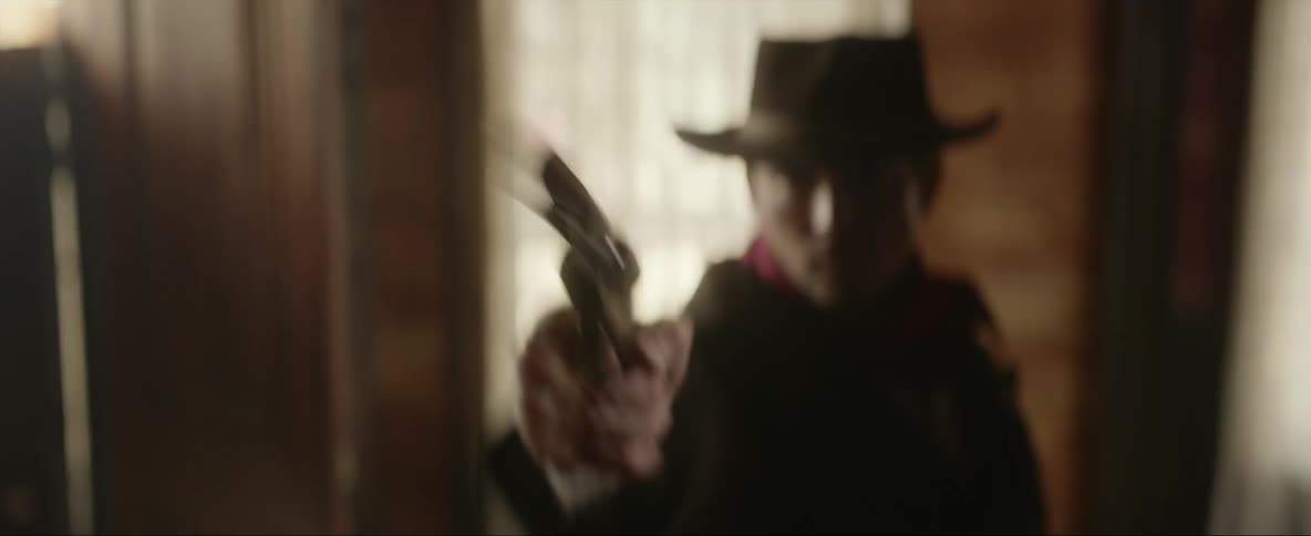 Man wearing old west garb practices drawing his six gun in room