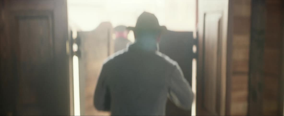 A man turns around and walks out of swinging doors with a man following behind