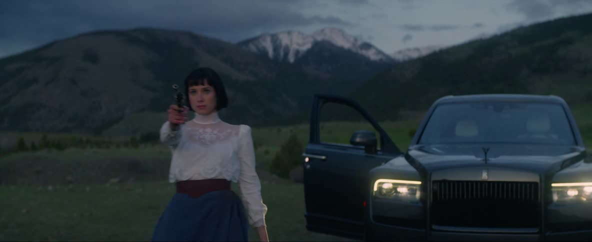 Headlights on a vehicle shining while a woman gets out welding a gun