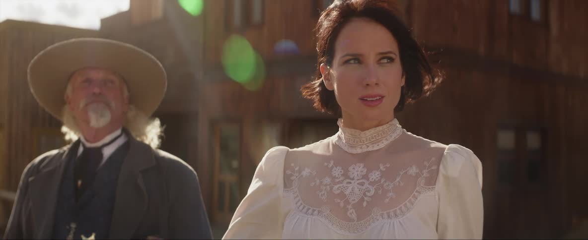 Woman wearing an old time dress walks away from two cowboys on a wild west town