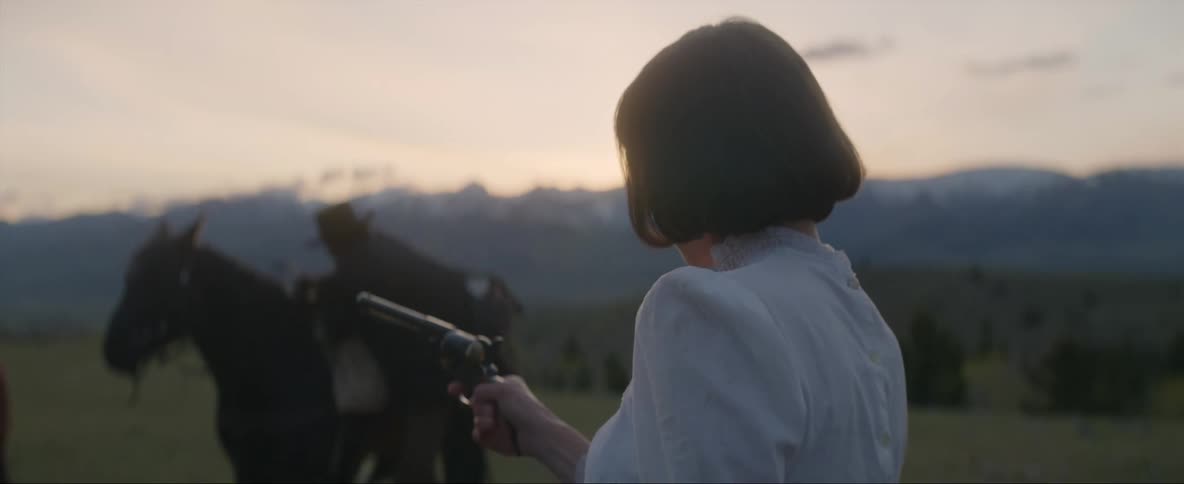 A woman turns around a pretends to shoot at a man on a horse with her pistol