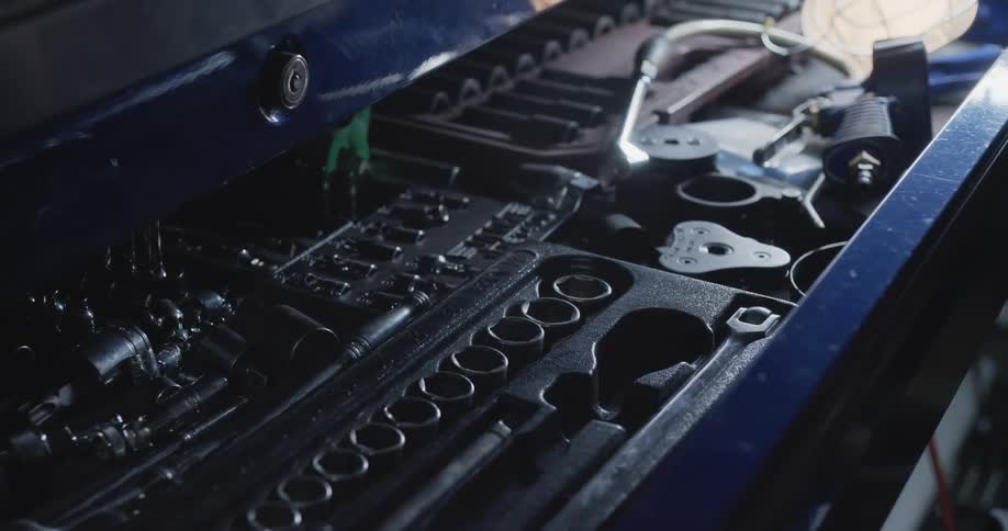 Sockets and wrenches sit in open blue colored toolbox