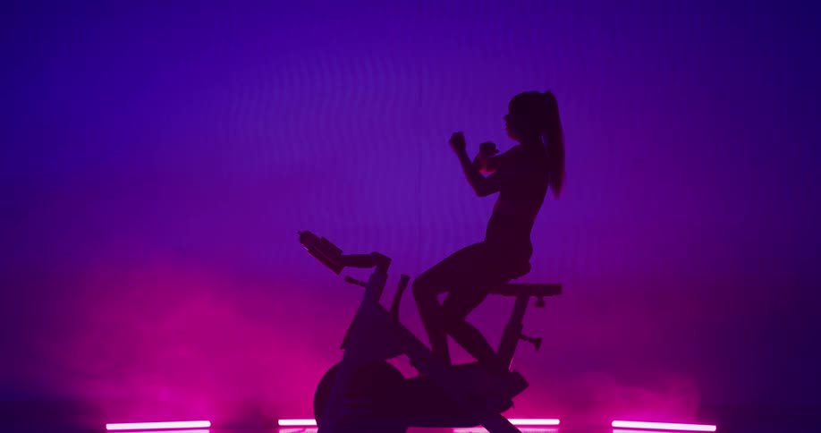 A woman is in a gym and is exercising on a bike